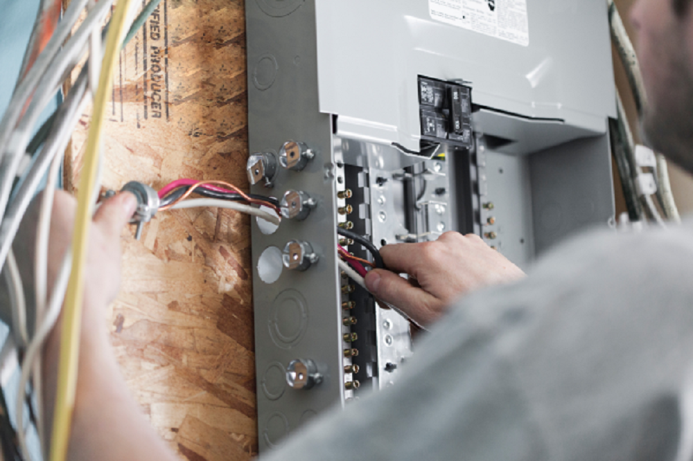 Commercial Service Electrician Installing Wires In Electrical Panel.